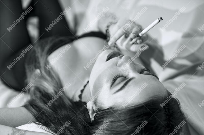 Young woman lounges with a cigarette on a plush sofa