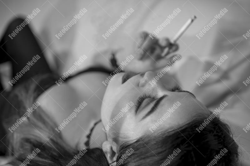 Young woman lounges with a cigarette on a plush sofa